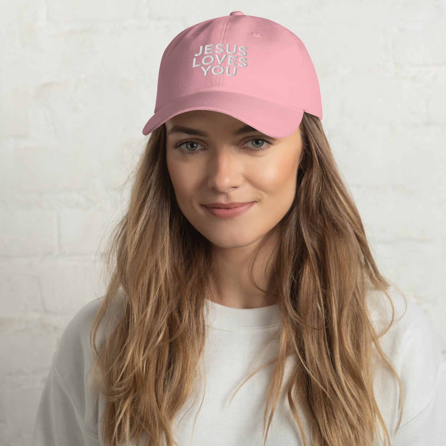 Person wearing a pink cap with 'JESUS LOVES YOU' text on a white background